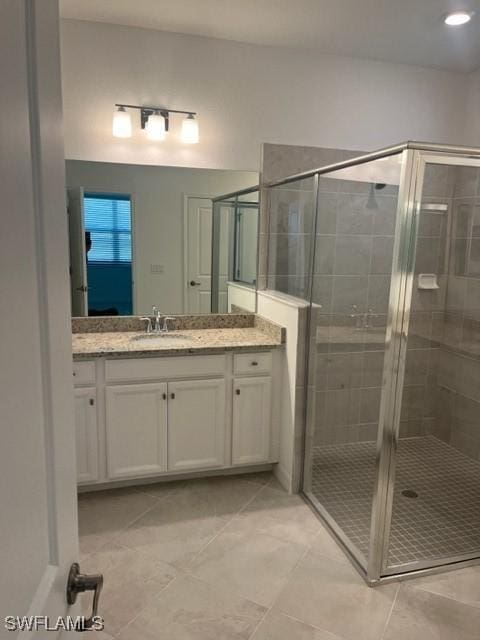 bathroom with tile patterned flooring, vanity, and walk in shower