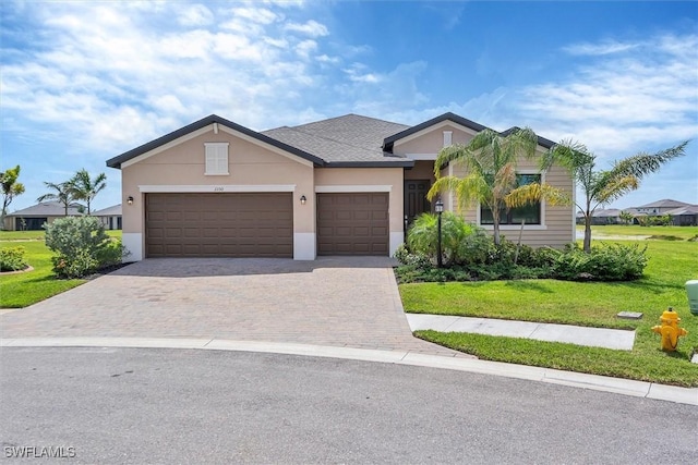 ranch-style home with a garage, stucco siding, a front yard, and decorative driveway