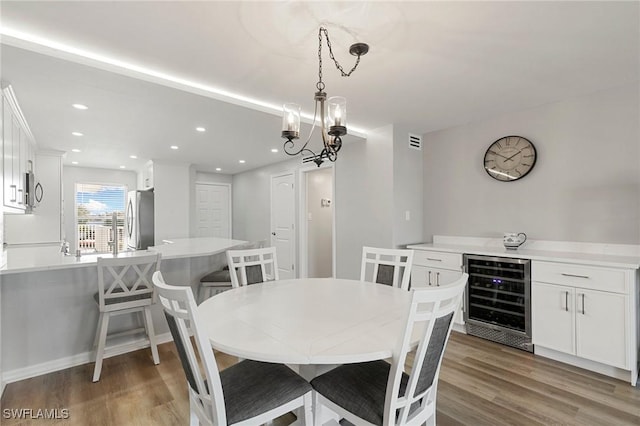 dining room featuring hardwood / wood-style flooring, beverage cooler, and an inviting chandelier