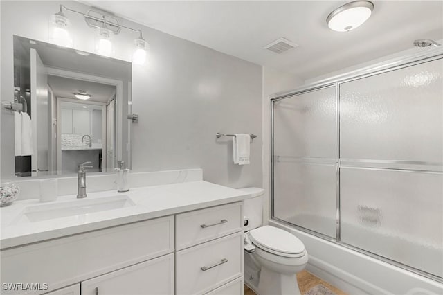 full bathroom with vanity, enclosed tub / shower combo, and toilet