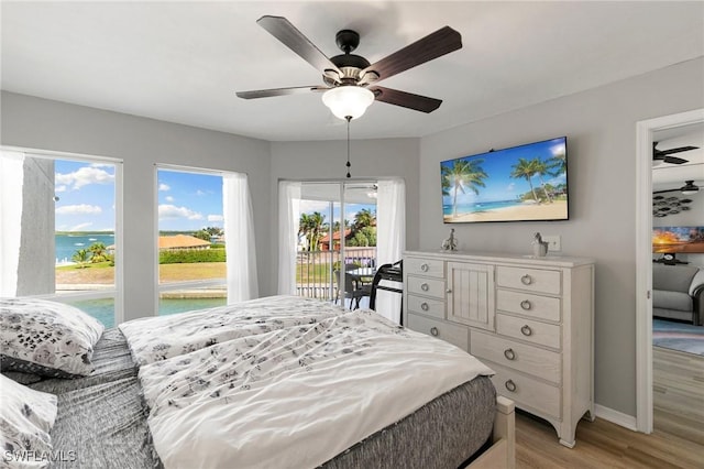 bedroom featuring ceiling fan, access to exterior, light wood-type flooring, and a water view