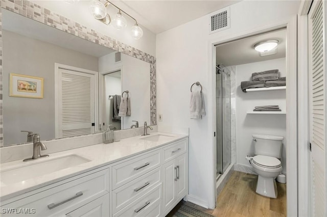 bathroom featuring hardwood / wood-style floors, vanity, a shower with door, and toilet