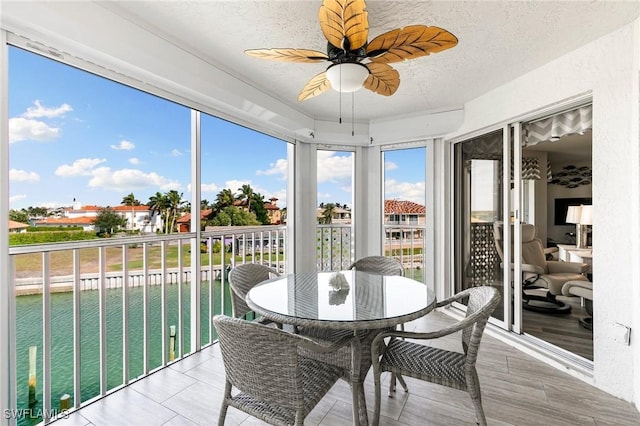 sunroom / solarium featuring ceiling fan and a water view