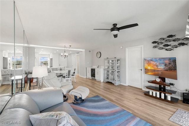 living room with ceiling fan with notable chandelier, light wood-type flooring, and beverage cooler