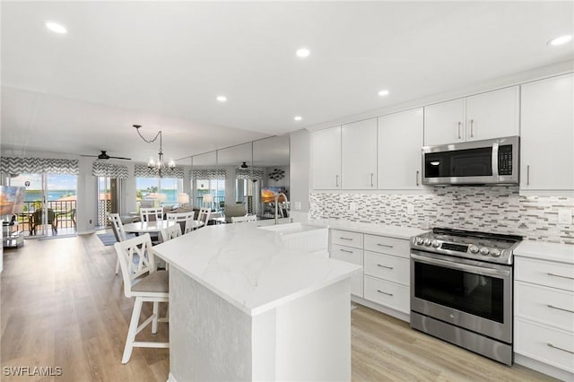 kitchen featuring a kitchen breakfast bar, white cabinetry, sink, and stainless steel appliances