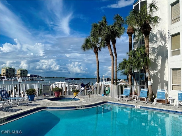 view of swimming pool featuring a water view and a hot tub