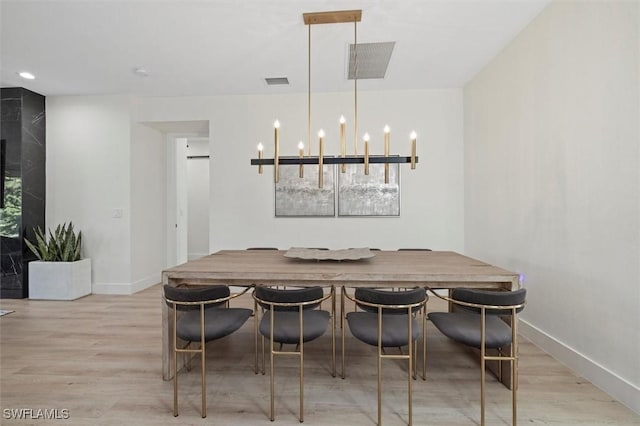 dining space with light hardwood / wood-style floors and an inviting chandelier