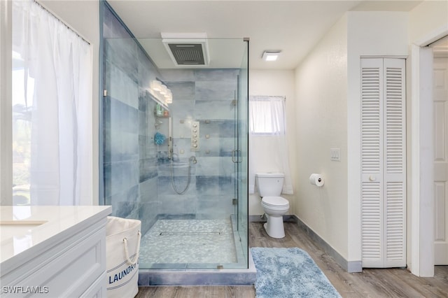 bathroom featuring hardwood / wood-style floors, vanity, toilet, and a shower with shower door