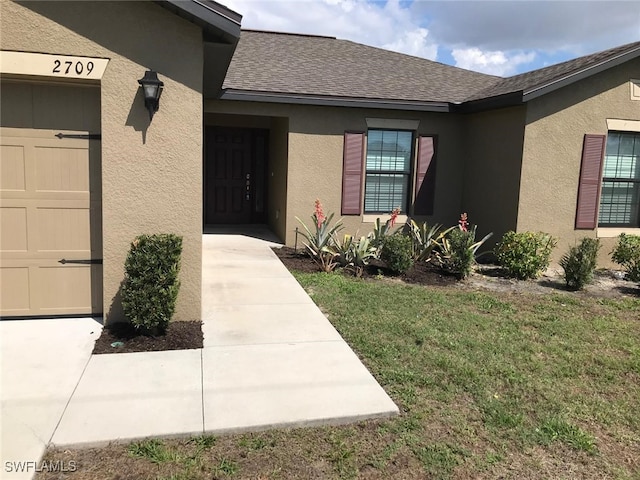 doorway to property with a lawn and a garage