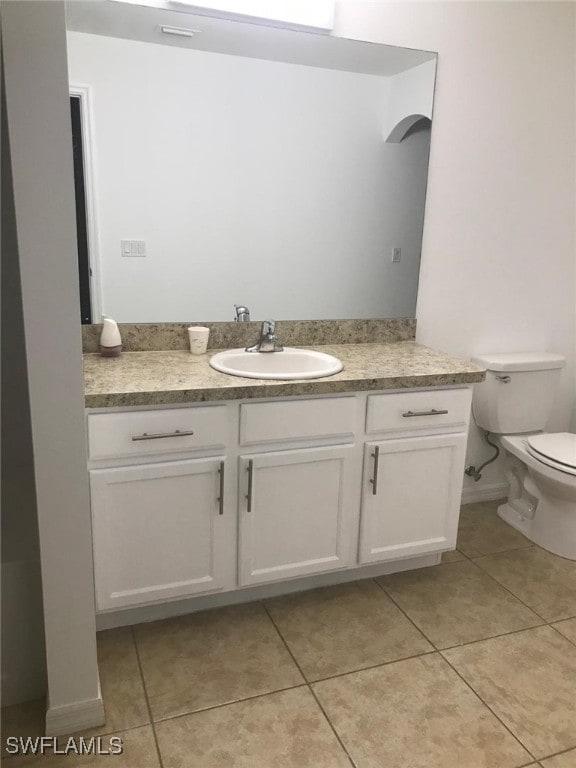 bathroom with toilet, vanity, and tile patterned floors