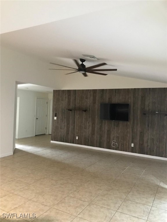 spare room featuring ceiling fan, wood walls, lofted ceiling, and light tile patterned floors