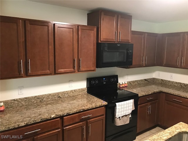 kitchen with light stone countertops, light tile patterned flooring, and black appliances