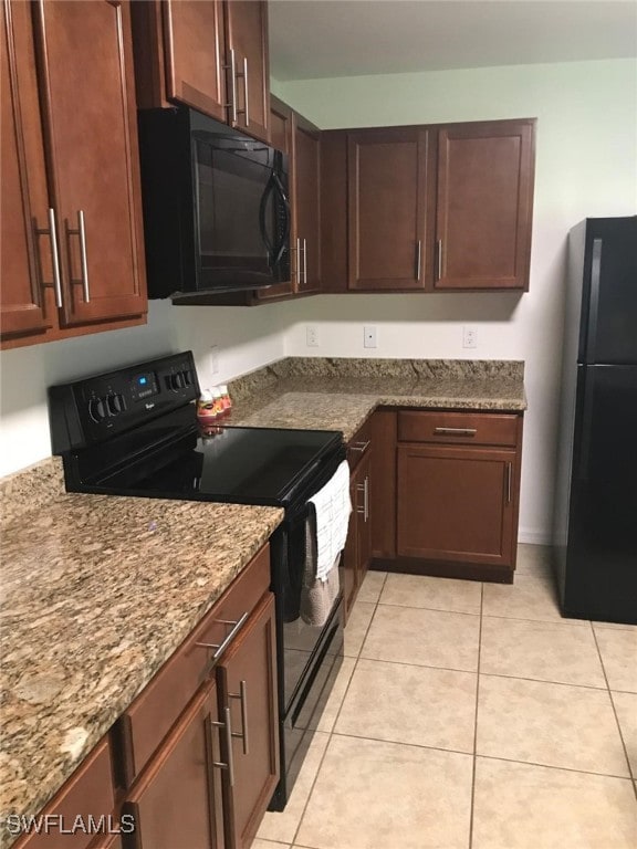 kitchen featuring light stone countertops, light tile patterned flooring, and black appliances