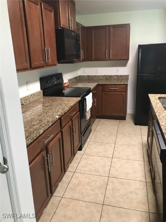 kitchen featuring black appliances, light tile patterned flooring, and stone counters