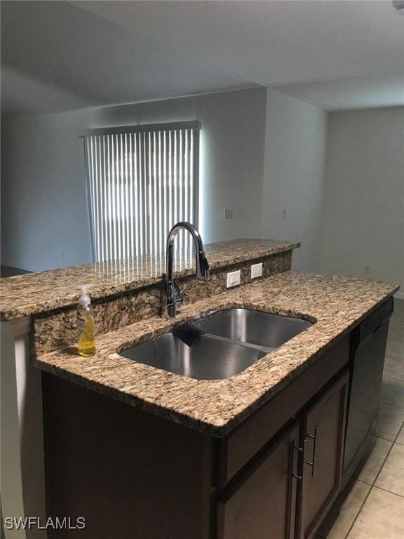 kitchen with sink, black dishwasher, light stone counters, an island with sink, and light tile patterned floors