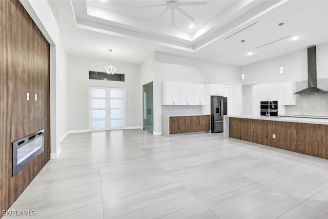 kitchen featuring white cabinets, stainless steel fridge, french doors, and wall chimney range hood