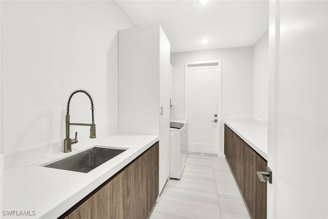 kitchen with light tile patterned floors, separate washer and dryer, and sink