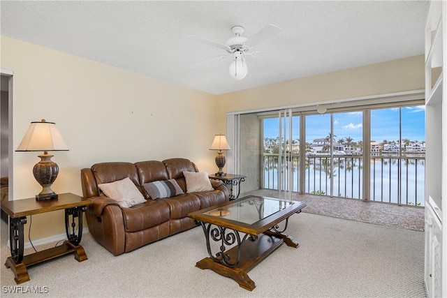 carpeted living room featuring a water view and ceiling fan