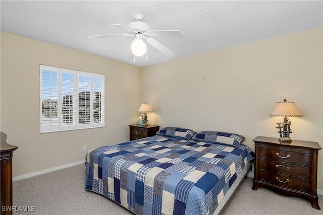 bedroom with ceiling fan, light colored carpet, and a textured ceiling