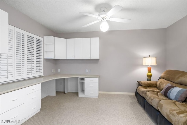 office featuring ceiling fan, light carpet, and built in desk