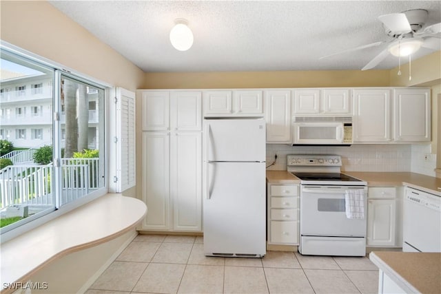 kitchen with white appliances, white cabinets, a textured ceiling, tasteful backsplash, and light tile patterned floors