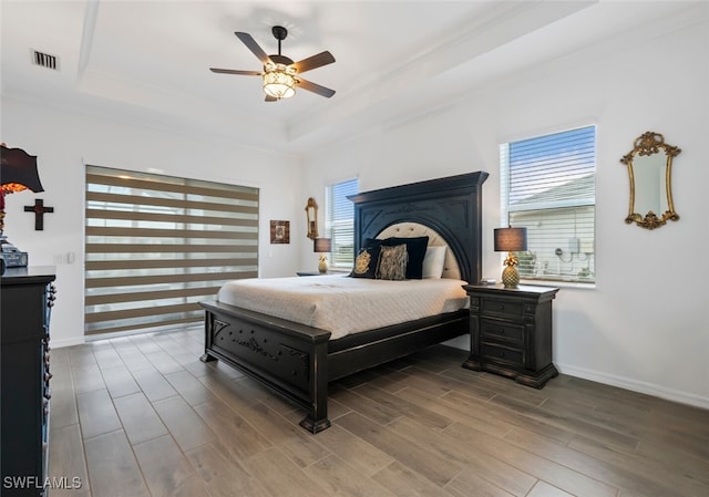 bedroom featuring ceiling fan, crown molding, multiple windows, and a tray ceiling