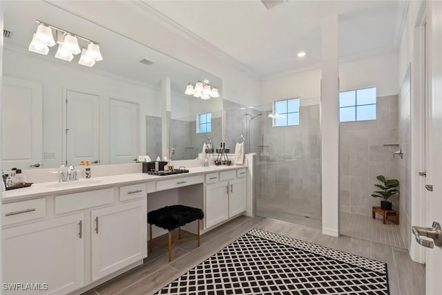 bathroom featuring vanity, ornamental molding, and tiled shower