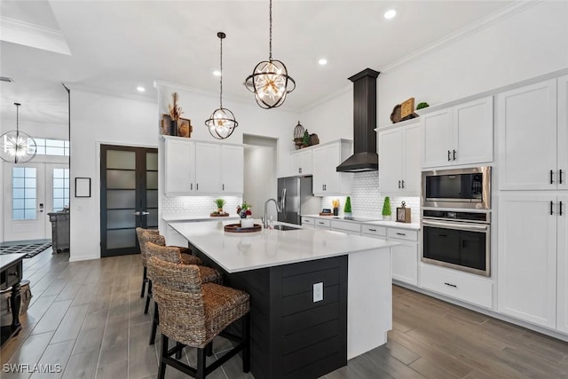 kitchen with french doors, white cabinets, hanging light fixtures, an island with sink, and appliances with stainless steel finishes