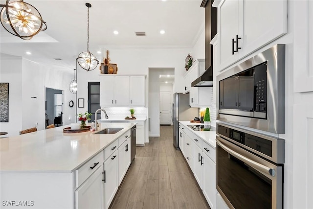 kitchen featuring white cabinetry, sink, stainless steel appliances, and a center island with sink