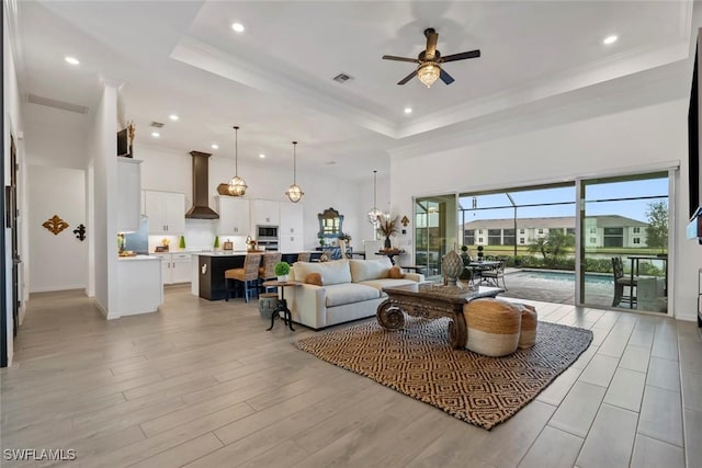 living room featuring ceiling fan, crown molding, and a tray ceiling