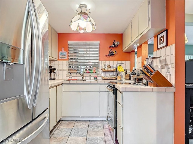 kitchen featuring sink, white cabinetry, light tile patterned floors, tasteful backsplash, and appliances with stainless steel finishes