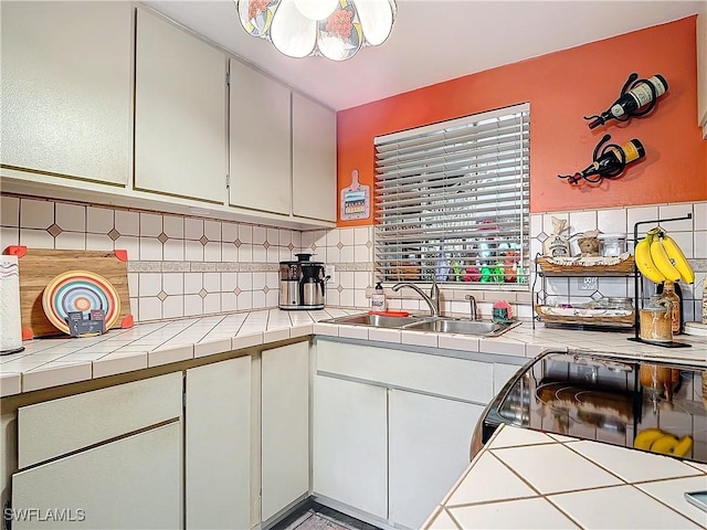 kitchen featuring black electric range oven, tile counters, sink, white cabinetry, and backsplash