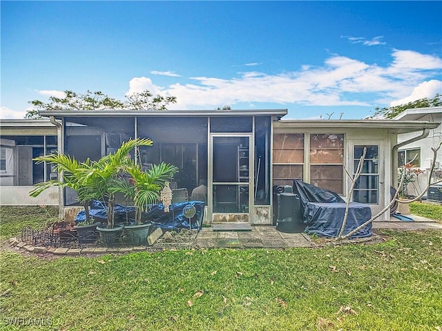 rear view of house with a lawn and a sunroom