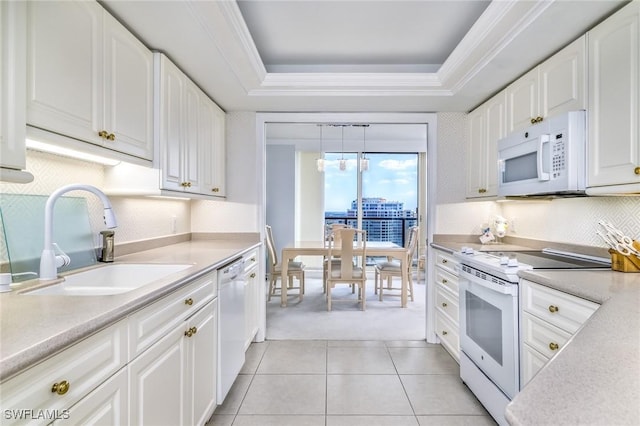 kitchen with a sink, white appliances, crown molding, light countertops, and a raised ceiling