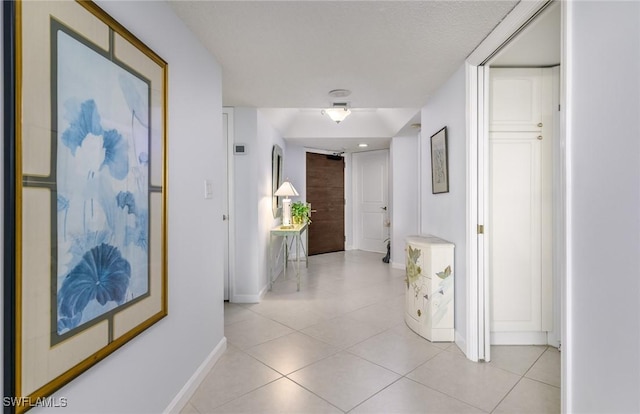 hallway featuring light tile patterned flooring and baseboards