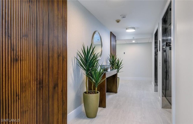 corridor featuring light wood finished floors and baseboards