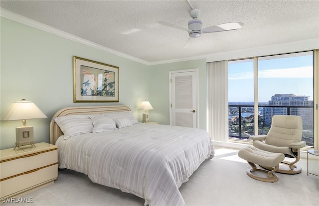 bedroom with light carpet, a view of city, ornamental molding, a textured ceiling, and ceiling fan