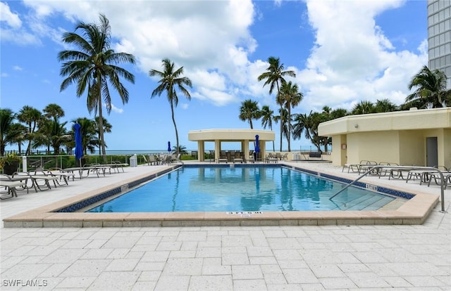 community pool with a patio area and fence