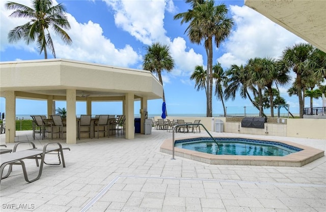 view of swimming pool featuring outdoor dry bar, a community hot tub, and a patio