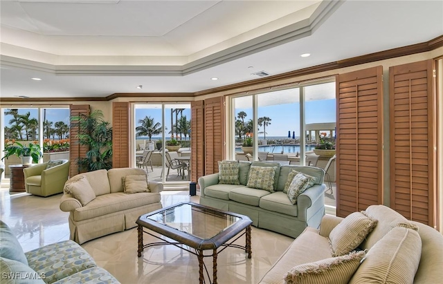 living room featuring a tray ceiling, visible vents, and crown molding