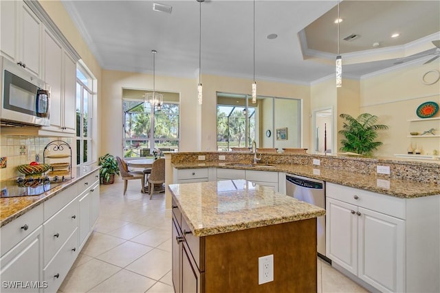 kitchen with stainless steel appliances, white cabinetry, a center island, and hanging light fixtures