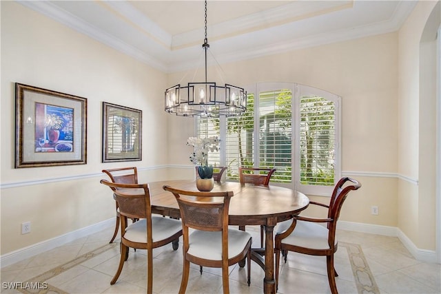 tiled dining space with a tray ceiling, ornamental molding, and an inviting chandelier