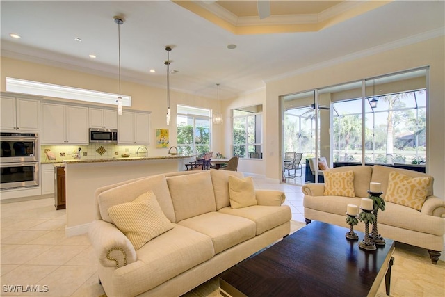 living room featuring light tile patterned floors, ornamental molding, and a tray ceiling