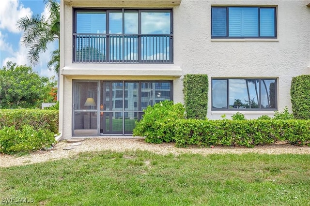 rear view of property with a balcony and a lawn