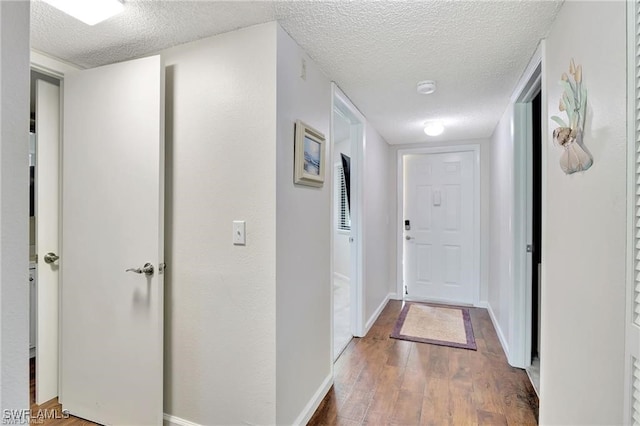 corridor with wood-type flooring and a textured ceiling