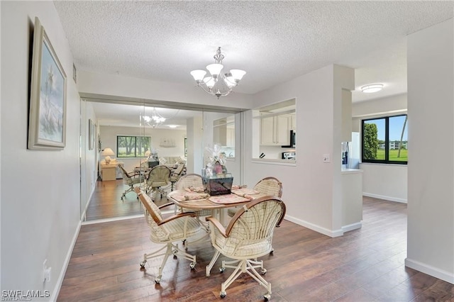 dining area with a notable chandelier, dark hardwood / wood-style flooring, and a textured ceiling