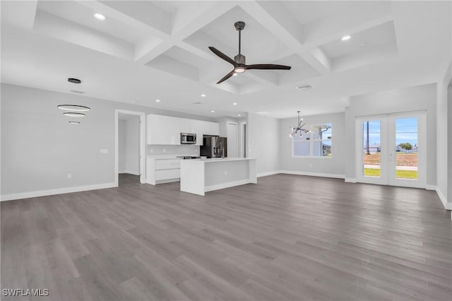 unfurnished living room featuring beam ceiling, ceiling fan with notable chandelier, wood-type flooring, and coffered ceiling