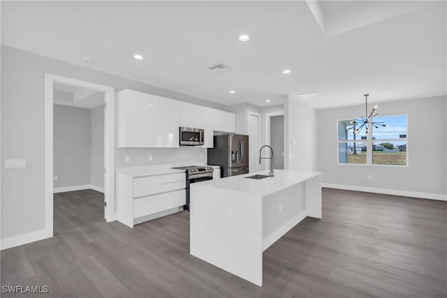 kitchen with a kitchen island with sink, an inviting chandelier, white cabinets, sink, and appliances with stainless steel finishes