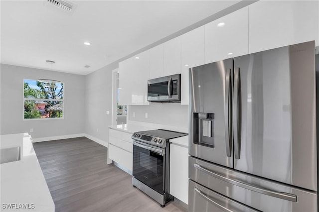 kitchen with white cabinets, stainless steel appliances, and light hardwood / wood-style flooring