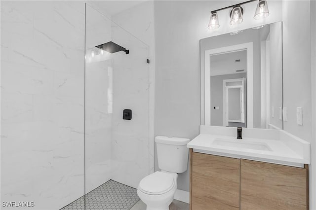 bathroom with tiled shower, vanity, and toilet